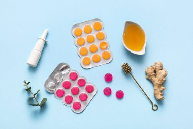 Su toplamış öksürük damlaları, mavi arka planda bal ve zencefil.