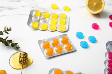 Okaliptüslü öksürük damlaları, beyaz grunge arka planda bal ve limon.