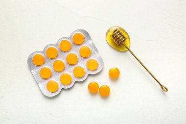 Öksürük pastili kabarcık ve beyaz arka planda bal