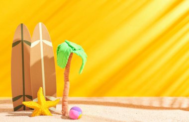 Deniz yıldızlı sörf tahtaları ve turuncu arka planda kumdaki plastikten yapılmış palmiye ağaçları.