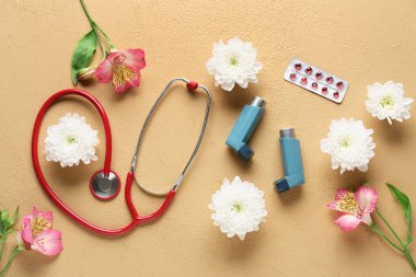 Steteskoplu astım spreyleri, haplar ve kahverengi arka planda güzel çiçekler.