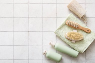 Havlulu masaj fırçaları, duş jeli ve beyaz fayanslı lifler, yakın plan.