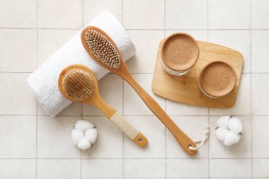 Beyaz seramik zemin üzerinde havlu, kavanoz ve pamuk ile masaj fırçaları