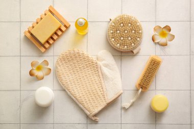 Beyaz karo arka planda eldiven, kozmetik ürünler ve sabunla masaj fırçaları