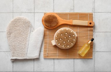 Beyaz karo zemin üzerinde eldiven, kozmetik ürün ve bambu paspas ile masaj fırçaları