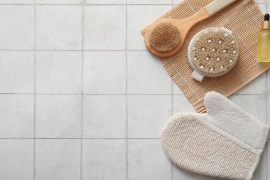 Beyaz karo zemin üzerinde eldiven, kozmetik ürün ve bambu paspas ile masaj fırçaları