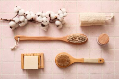 Kozmetik ürünü, sabun ve pamuk çiçekli masaj fırçaları pembe karo arka planda