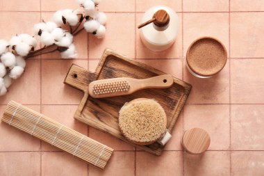 Masaj fırçaları, kozmetik ürünleri ve bej fayanslı pamuk çiçekli tepsi