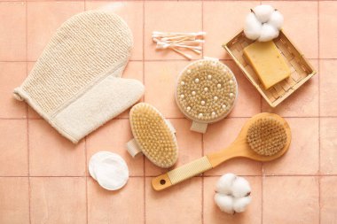 Bej karo arka planda eldiven, sabun ve pamuk içeren masaj fırçaları