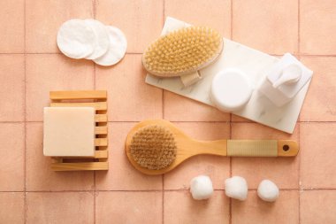 Bej karo arka planda kozmetik ürünleri, sabun ve pamuk pedleri ile masaj fırçaları