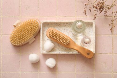 Masaj fırçalı tepsi, kozmetik ürünler ve pembe fayanslı pamuk.