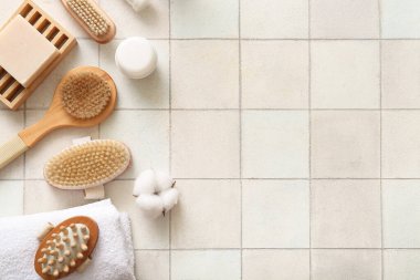 Sabunla masaj fırçaları, kozmetik ürünleri ve beyaz fayans üzerine havlu