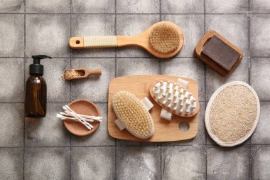 Sabunlu masaj fırçaları, duş jeli ve gri fayanslı pamuklu çubuklar.
