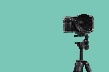 Turkuaz arka plana karşı tripodda profesyonel kamera