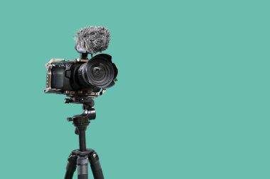 Turkuaz arka plana karşı tripodda profesyonel kamera