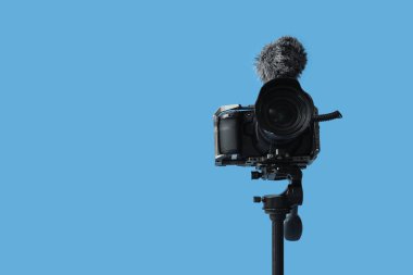 Mavi arkaplana karşı tripodda profesyonel kamera, yakın plan