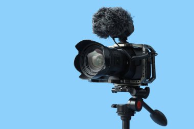 Mavi arkaplana karşı tripodda profesyonel kamera, yakın plan