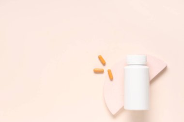 Boş plastik vitamin şişesiyle dekoratif podyum ve bej arka planda haplar