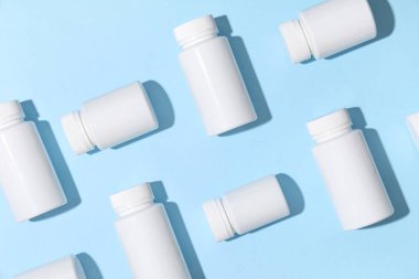 Mavi arka planda birçok boş plastik vitamin şişesi