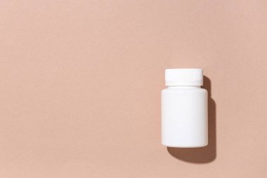 Kahverengi arka planda boş plastik vitamin şişesi