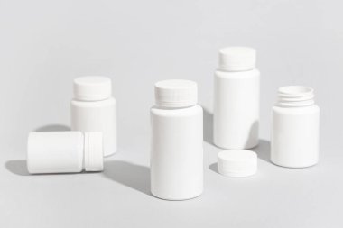 Gri arka planda birçok boş plastik vitamin şişesi