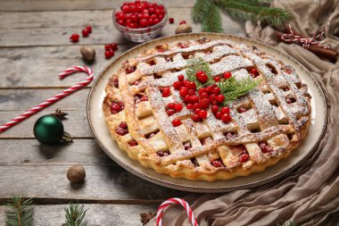 Ahşap arka planda lezzetli yaban mersinli turta ve baston şekerli tabak, yakın plan. Noel kutlaması