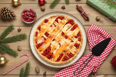 Köknar dalları ve ahşap arka planda Noel topları olan lezzetli kızılcık turtası.