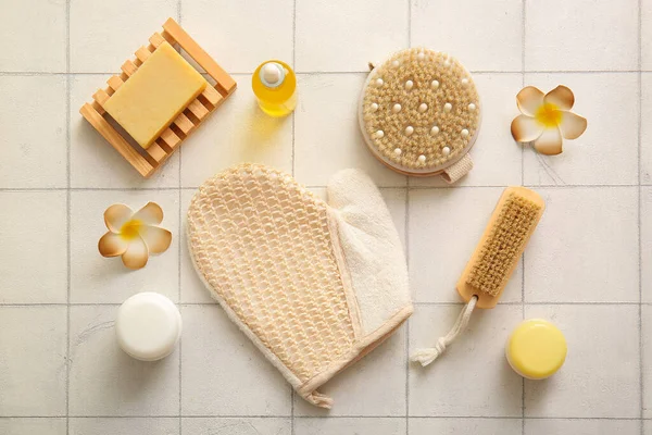 Beyaz karo arka planda eldiven, kozmetik ürünler ve sabunla masaj fırçaları