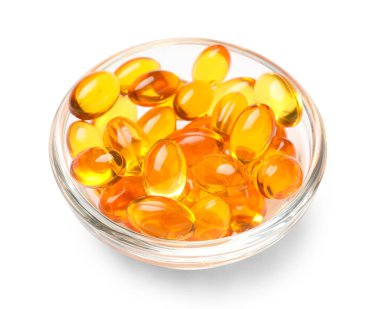 Beyaz zemin üzerinde E vitamini kapsülleri olan kase