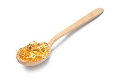 Beyaz zemin üzerinde E vitamini kapsülleri olan tahta kaşık.