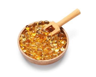 Beyaz arka planda E vitamini kapsülleri ile kase ve kepçe