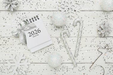 Beyaz ahşap arka planda Noel topları, konfeti ve kağıt takvim kompozisyonu, yakın plan