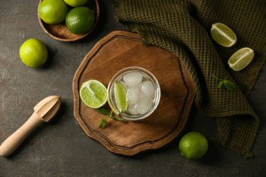 Bir bardak nane yaprağı ve siyah arka planda ahşap sıkacağı ile doldurulmuş limon suyu.