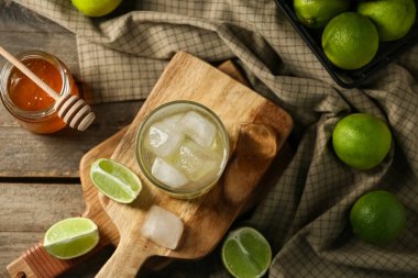 Bir bardak limonlu su ve ahşap zeminde bir kavanoz bal.