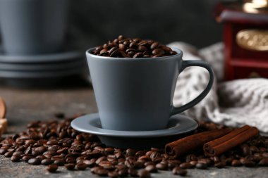 Kahve çekirdekli kahve fincanı ve gri arkaplanda tarçın.
