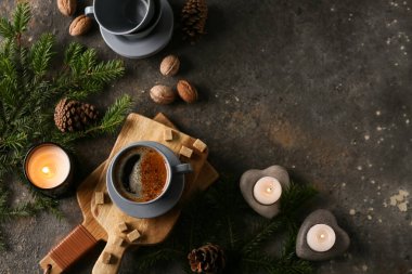 Bir fincan mumlu kahve, çam kozalakları ve koyu grunge arka planda köknar ağacı dalları.