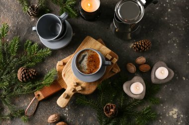 Bir fincan mumlu kahve, çam kozalakları ve koyu grunge arka planda köknar ağacı dalları.