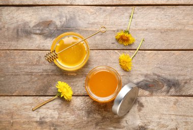 Kavanoz ve karahindiba ile ahşap zemin üzerinde bal