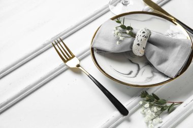 Katlanmış peçete ve ahşap beyaz arka planda altın çatal bıçaklı tabak.