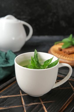 Bir fincan taze nane çayı, limon ve tarçınlı çaydanlık grunge siyah arka plan