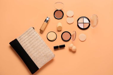 Makyaj ürünleri ve bej arka planda güzel çiçeklerle süslü şık bir makyaj çantası.