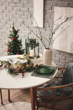 Ağaç dalları ve Noel topları olan vazo yemek masasında.