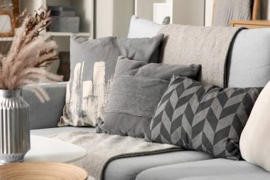 Oturma odasındaki şık gri kanepenin yanındaki masada güzel çiçekli vazo.