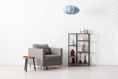 Modern odada raf ünitesi ve gri asılı lambası olan şık bir koltuk.