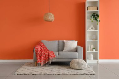 Gri kanepeli, puf ve raf üniteli şık bir oturma odası.