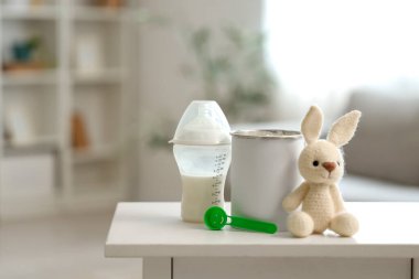 Bebek sütü formülü ve oyuncak tavşanla dolu şişe masada, yakın plan.