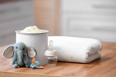 Bebek sütü formülü, emzik, oyuncak ve battaniye mutfakta, yakın plan.