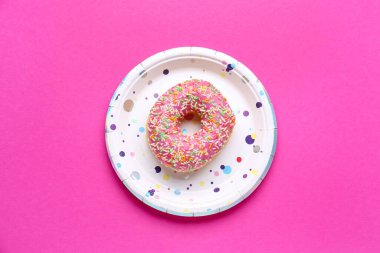 Pembe arka planda çörekli tek kullanımlık kağıt tabak.