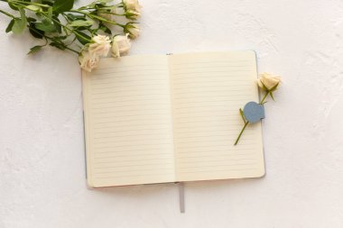 Boş bir defter ve açık arkaplanda güzel güller.