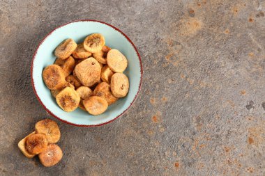 Koyu arkaplanda kurutulmuş incir kâsesi.